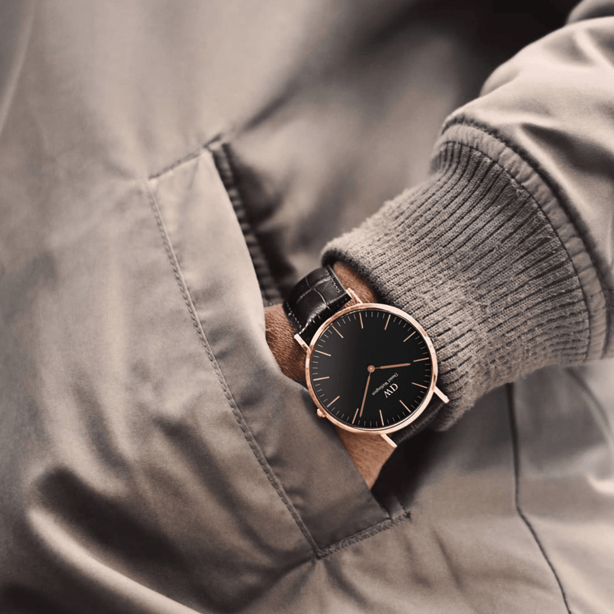 A man wearing the Classic York Black Rose Gold watch with a black dial, rose gold case, and dark brown croc-embossed leather strap, styled casually with his hand in a jacket pocket.