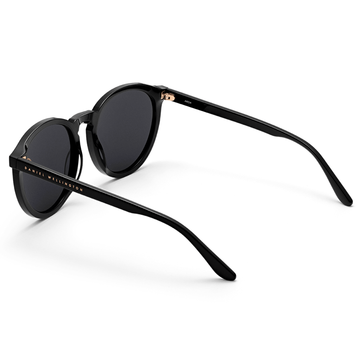 Arch Bio-Acetate Black sunglasses with round black frames, deep black lenses, and Daniel Wellington branding on the temple, shown from a rear angle to highlight the slim, lightweight bio-acetate arms.