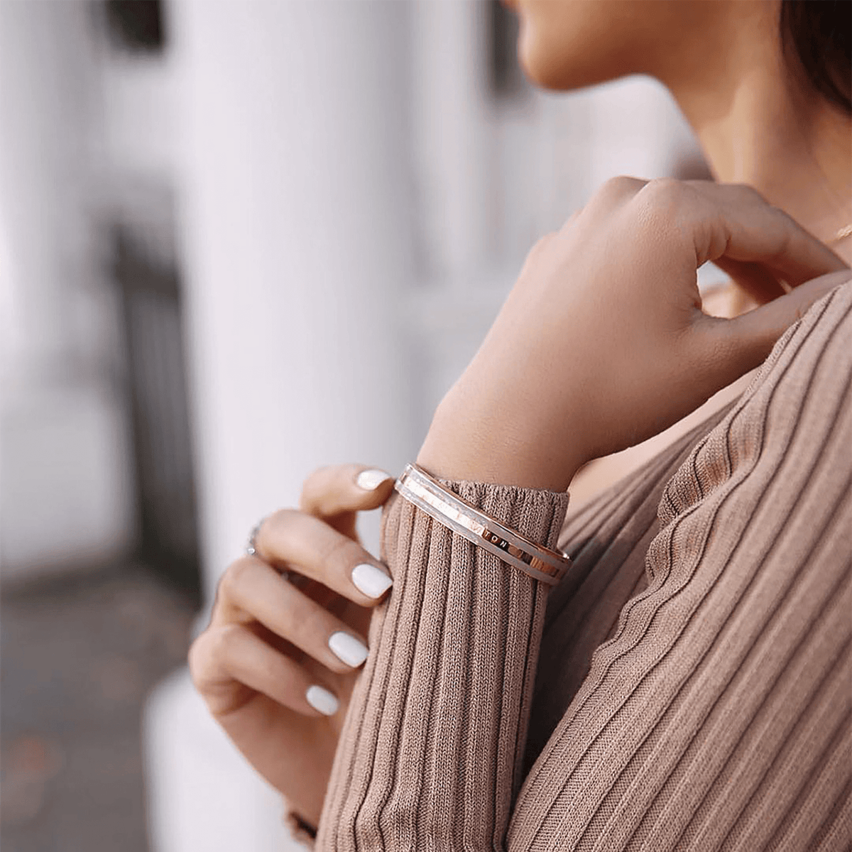 Emalie Bracelet Desert Sand Rose Gold worn on a woman’s wrist, showing its rose gold and desert sand enamel cuff paired with a neutral ribbed top for a stylish, everyday look.