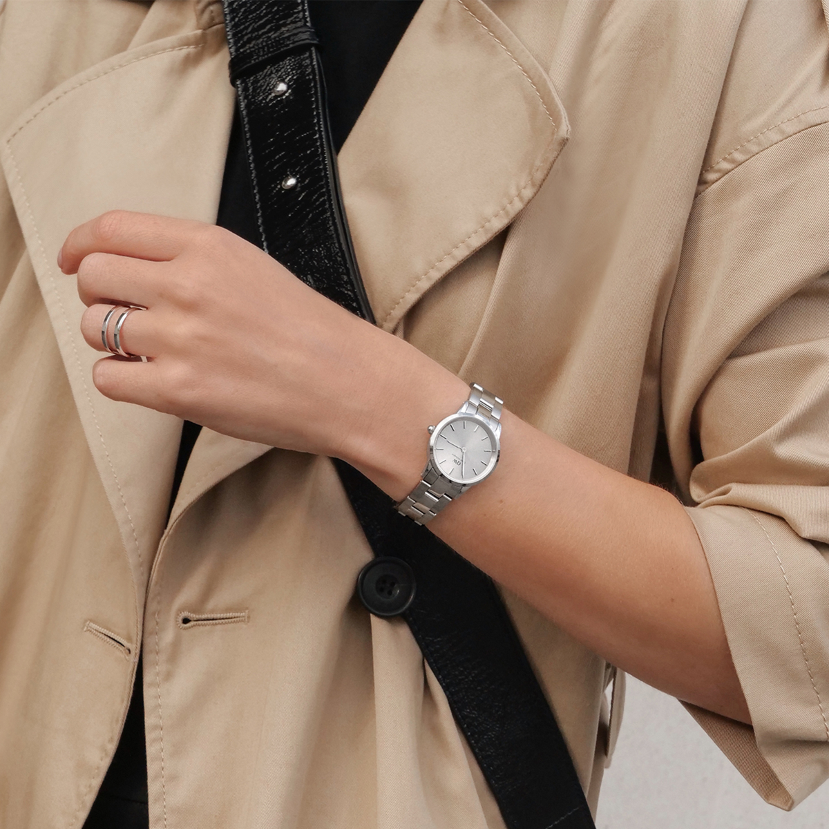 Iconic Link Unitone Silver ladies watch with a polished stainless steel bracelet and minimalist silver dial, worn with a beige trench coat for a sophisticated everyday look.