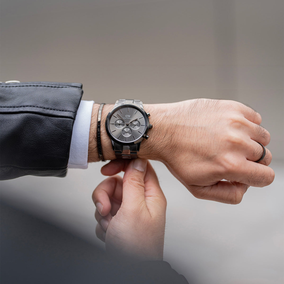 Classic Bracelet Graphite worn alongside a stainless steel Daniel Wellington watch, showcasing the slim graphite cuff and engraved branding for a modern, layered look suitable for everyday wear.