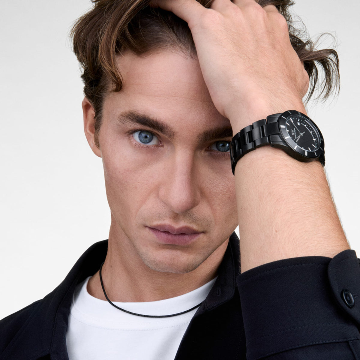 A man wearing the Iconic Paradigma Link Black watch, showing its bold black dial, index bezel, and polished link bracelet styled with a casual white t-shirt and dark shirt for a modern, everyday look.