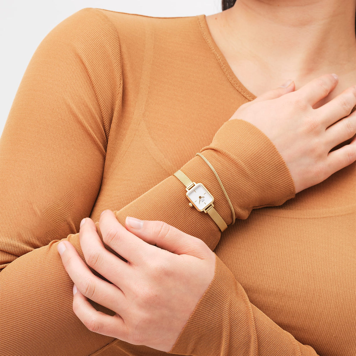 A woman wearing the Tide Mesh Bracelet Evergold 1.8 alongside a gold mesh watch, showing the slim gold bracelet’s delicate mesh texture and refined styling paired with casual attire.