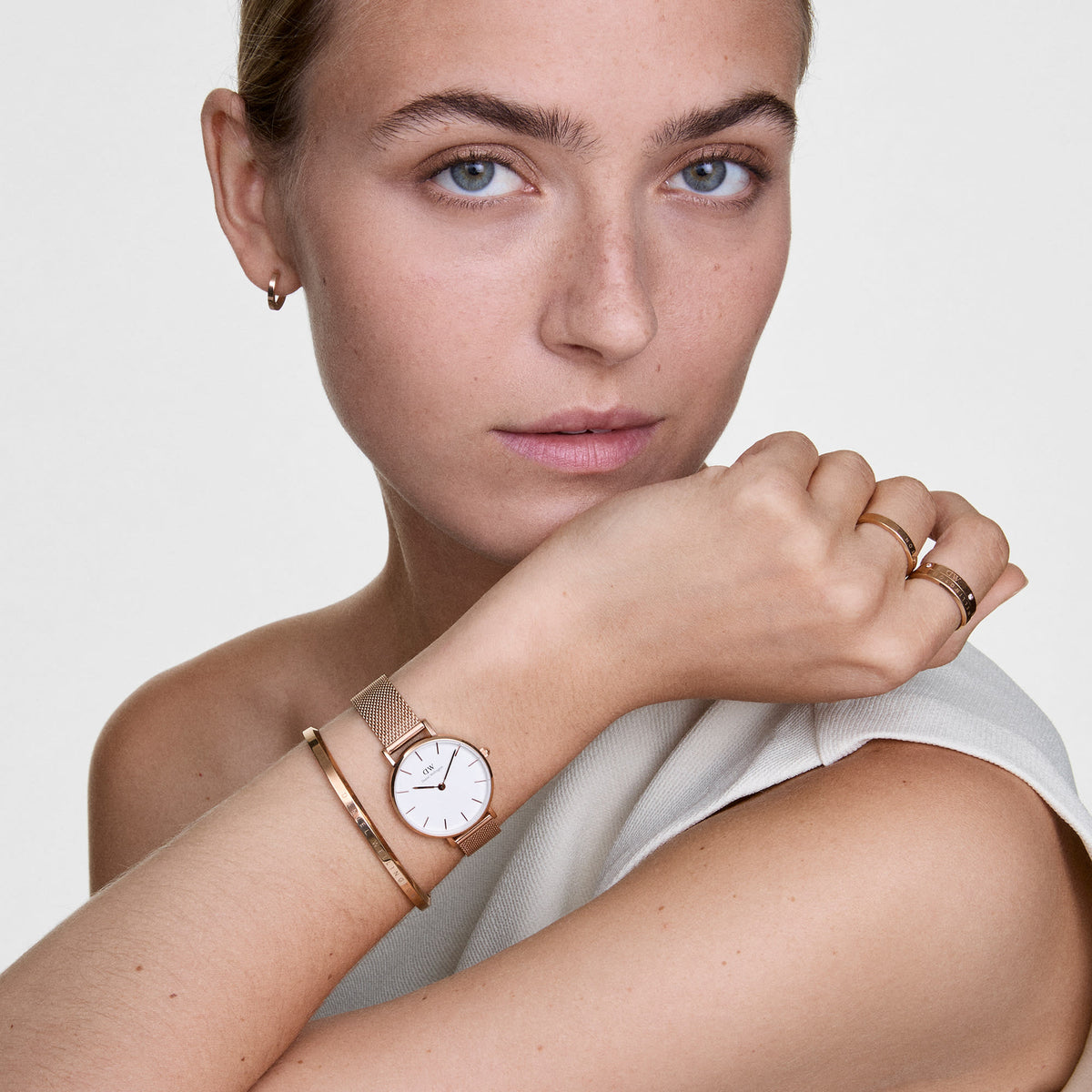A woman wears the Classic Lumine Ring Rose Gold on her finger, styled with a matching rose gold watch and bracelet, highlighting the ring’s slim band, polished finish, and subtle crystal details for an elegant, coordinated look.