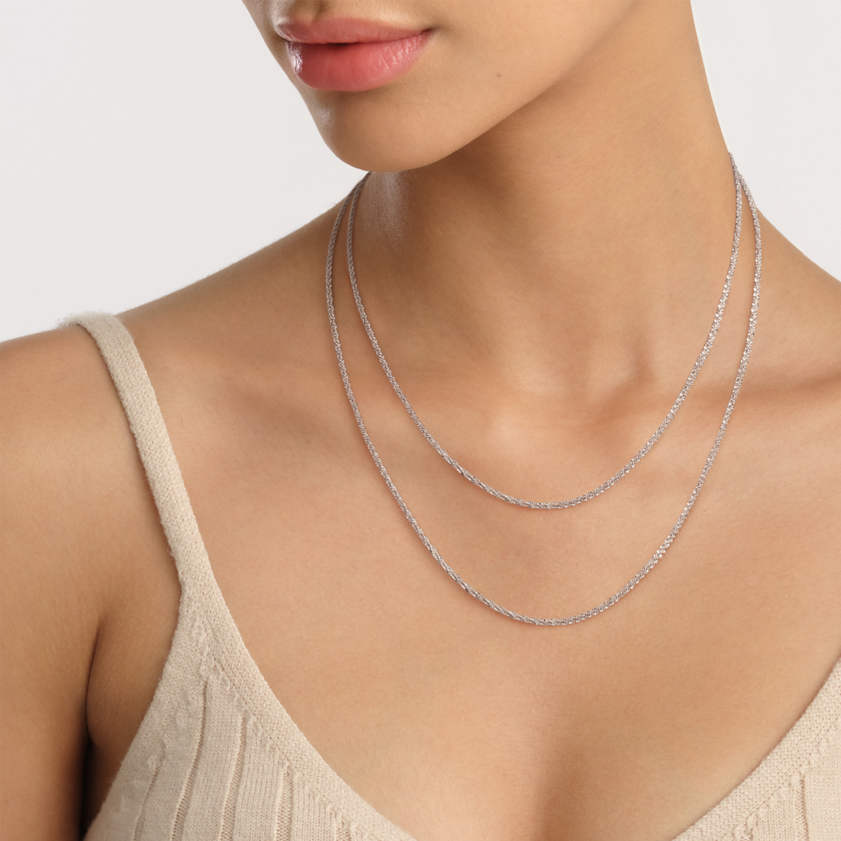 Twisted Chain Necklace S in silver, styled as a layered minimalist accessory on a woman wearing a neutral knit top, highlighting its refined twisted links and adjustable length.