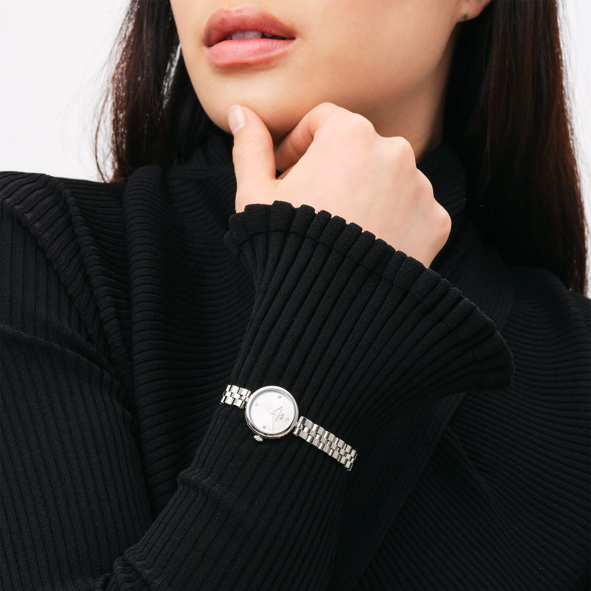 A woman wearing the Elan Lumine Unitone Silver ladies watch with a stainless steel link bracelet and minimalist silver dial, styled with a black ribbed long-sleeve top for a refined, everyday look.