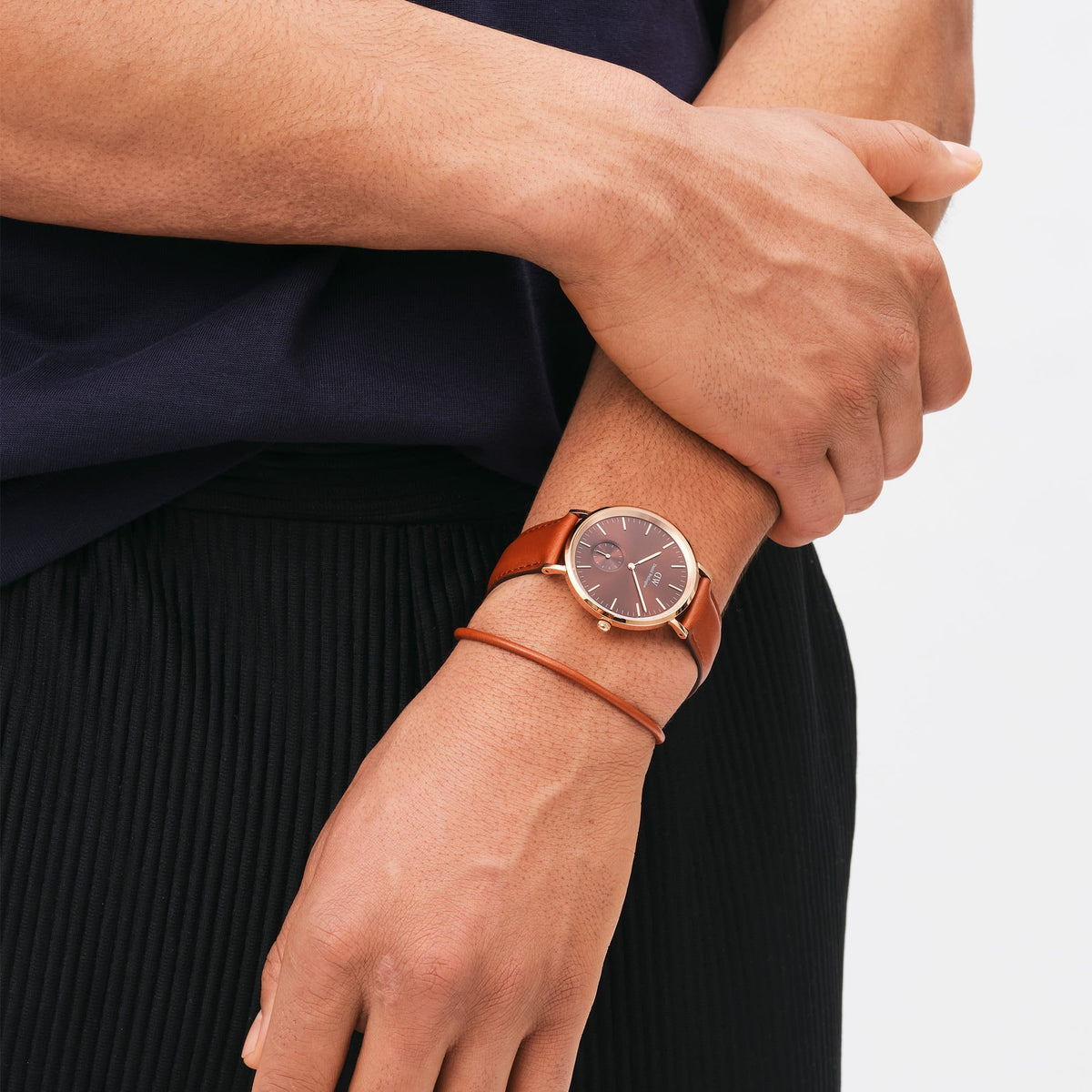 St Mawes Bracelet Rose Gold worn alongside a matching brown leather watch, highlighting the slim profile and minimalist design suitable for everyday and formal wear.