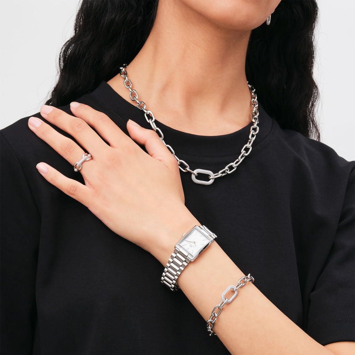 Bound 3-Link Silver watch styled on a wrist with matching silver jewellery, showcasing its rectangular case, three-link bracelet, and minimalist white dial for a modern everyday look.