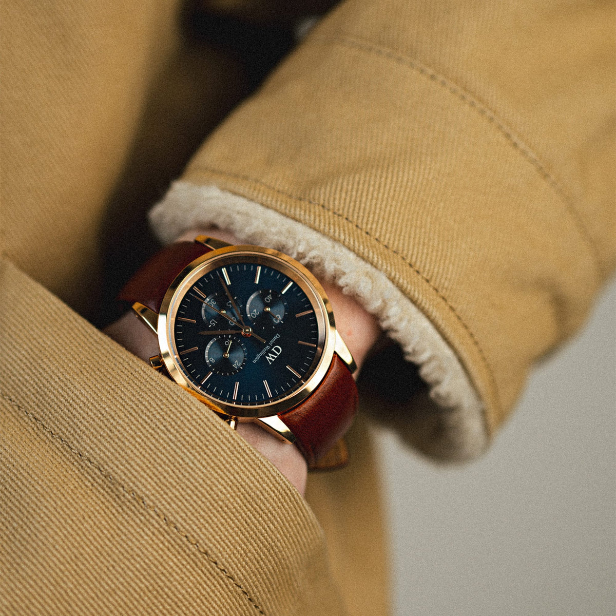 Iconic Chronograph St Mawes Arctic Rg men's watch with a blue dial, rose gold case, and brown leather strap, worn with a tan jacket for a stylish and versatile everyday look.