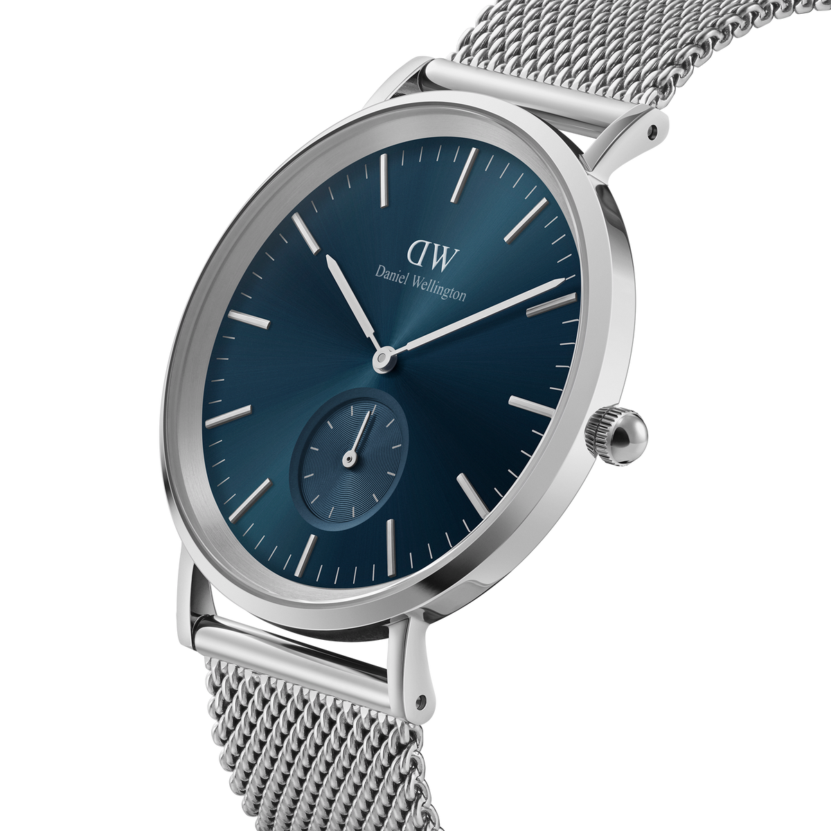 Classic Multi-Eye Sterling Arctic men's watch with a round silver case, deep blue dial, minimalist hour markers, and a stainless steel mesh strap, shown from a side angle to highlight its slim profile and elegant design.