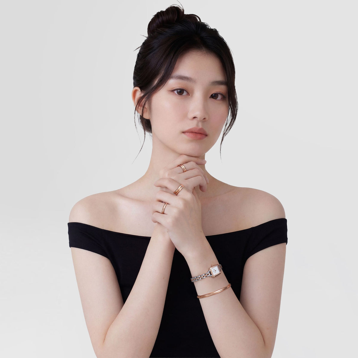 A woman wearing the Quadro Mini Arch 3-Link Two Tone Rose Gold ladies watch, styled with matching rose gold jewellery and a black off-shoulder top, highlighting the watch’s petite rectangular case and elegant two tone bracelet.
