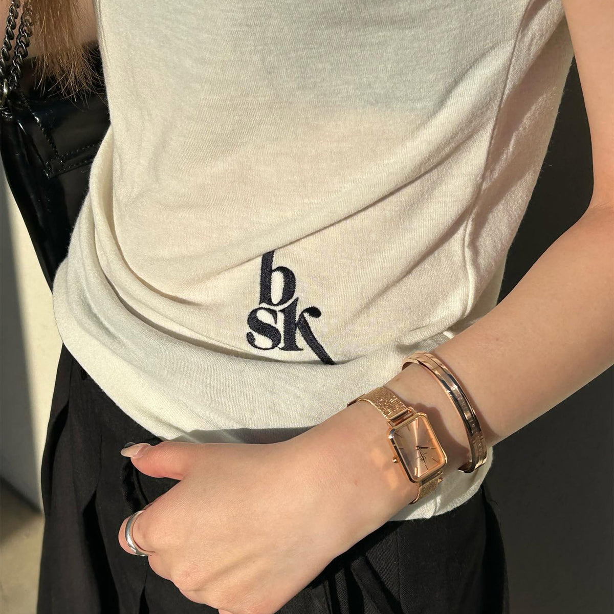 A woman wearing the Quadro Pressed Unitone rose gold watch with a pressed mesh strap, styled alongside a matching rose gold bangle and casual outfit, highlighting its slim profile and versatile elegance for everyday wear.