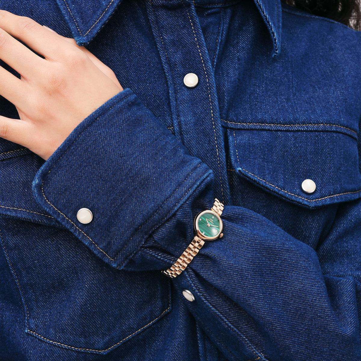 Elan Lumine Malachite Rose Gold ladies watch with a slim rose gold bracelet and green malachite dial, worn with a blue denim shirt for a stylish, casual look.