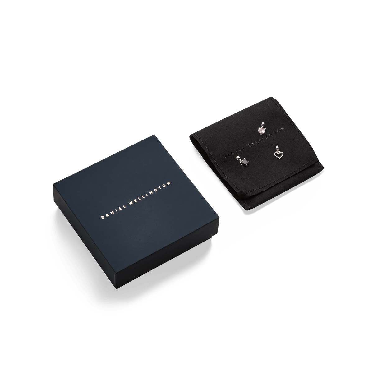 Daniel Wellington gift box alongside a black jewellery pouch, showcasing three silver charms including a heart, a crystal, and a crescent shape.