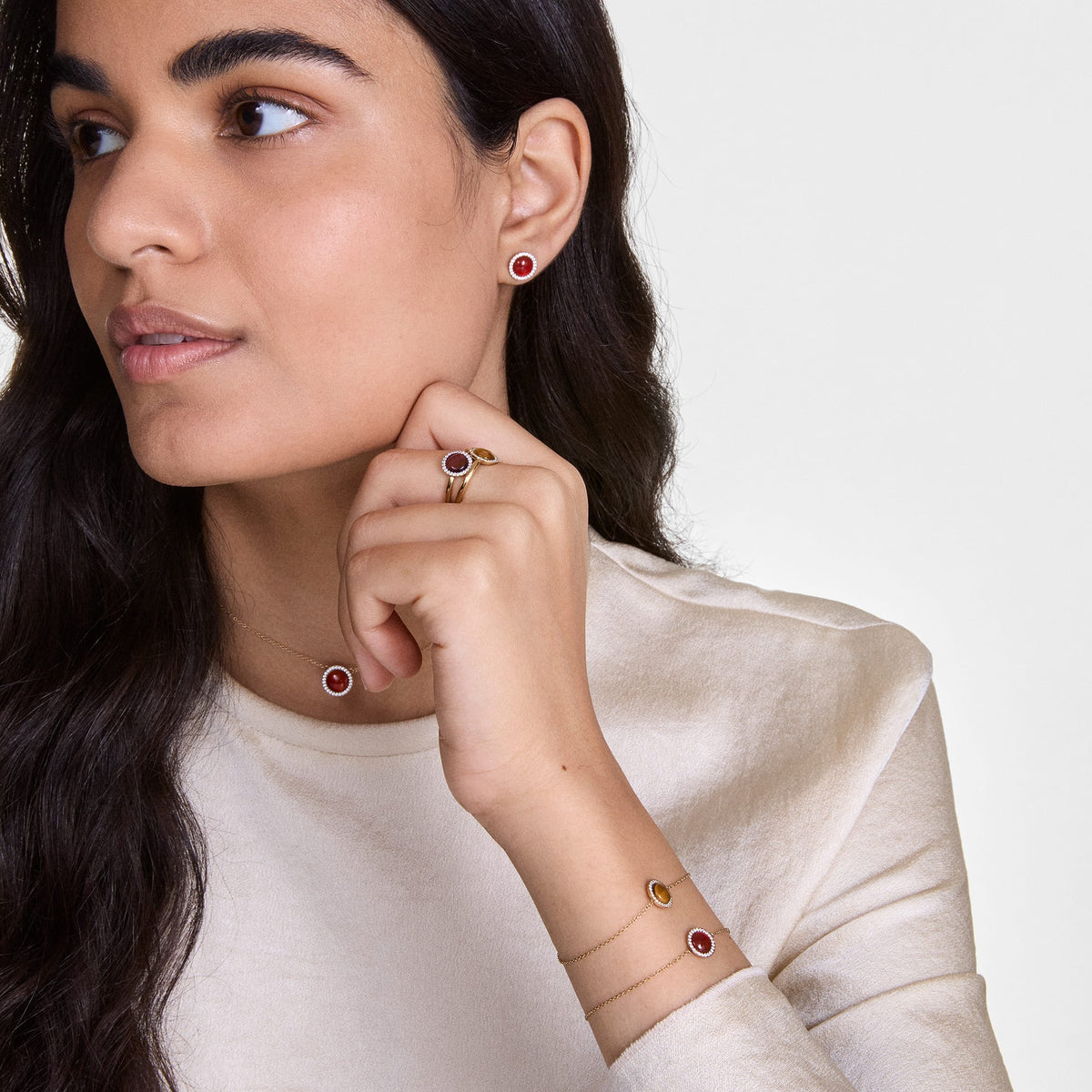 A woman wearing the Audrey Necklace Red Agathe Silver, featuring a red agate pendant with white cubic zirconia crystals on a fine silver chain, styled with matching earrings, ring, and bracelets for an elegant, coordinated look.