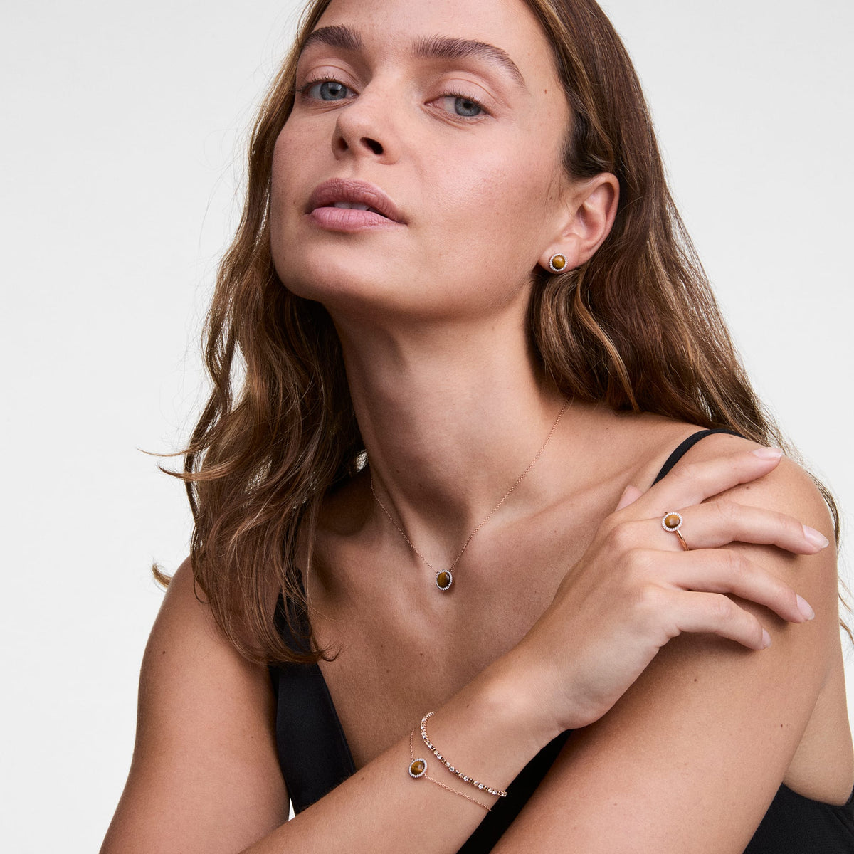 Woman wearing the Audrey Necklace Tiger Eye Silver, styled with matching tiger eye earrings, bracelet, and ring, showcasing the necklace’s domed tiger eye pendant and polished silver chain.