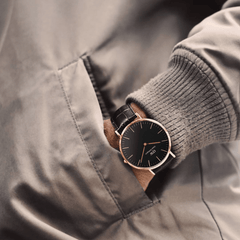A man wearing the Classic York Black Rose Gold watch with a black dial, rose gold case, and dark brown croc-embossed leather strap, styled casually with his hand in a jacket pocket.