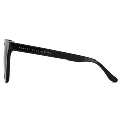 Side view of the Grande Bio-Acetate Black sunglasses showing the glossy black temple with Daniel Wellington branding and the oversized square frame design.