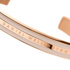 Emalie Bracelet Desert Sand Rose Gold close-up showing the engraved Daniel Wellington branding, rose gold finish, and desert sand enamel detail on the cuff.