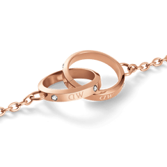 Close-up of the Classic Lumine Unity Rose Gold necklace pendant, showing two interlocking rose gold rings with crystal accents and a polished finish on a delicate chain.