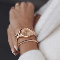 Iconic Link Unitone RG rose gold ladies watch with a polished link bracelet and matching rose gold dial, worn on a wrist alongside a rose gold bangle, styled with a white textured sleeve for a refined everyday look.