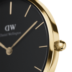 Close-up of the Petite Sheffield Black Gold watch showing the polished gold stainless steel case, minimalist black dial with slim gold markers, and detailed crown design.