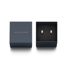Emalie Earrings Rose Gold Satin White displayed in a navy Daniel Wellington gift box, showing the pair of minimalist rose gold huggie earrings with satin white enamel detail, ideal for gifting.