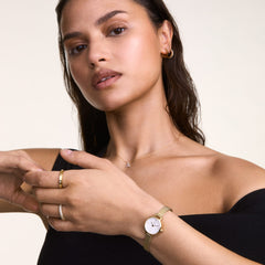 A woman wears the Crystal Zodiac Chain Necklace Silver with a Capricorn zodiac pendant set with sparkling crystals, styled with gold jewellery and a black top for a modern, elegant look.