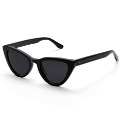 Lynx Bio-Acetate Black sunglasses featuring a bold cat eye shape, glossy black bio-acetate frame, dark nylon lenses, and subtle Daniel Wellington branding on the temples.