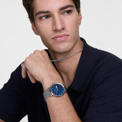 A man wearing the Classic Day Display Sterling Arctic watch with a blue patterned dial and stainless steel mesh strap, styled with a dark shirt for a smart, modern look.