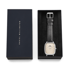 Marlon Sheffield Linen Silver men's watch presented in a sleek black Daniel Wellington gift box, featuring a rectangular stainless steel case, linen-textured dial, and classic black leather strap.