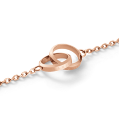 Close-up of the Elan Unity Bracelet Rose Gold showing two polished interlocking rings engraved with branding, attached to a fine rose gold chain.