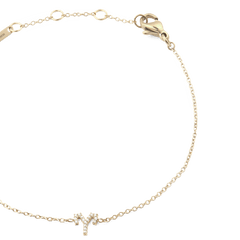 Close-up of the Crystal Zodiac Chain Bracelet Gold, featuring a fine gold chain with adjustable sizing rings and a crystal-encrusted Aries zodiac charm at the centre.
