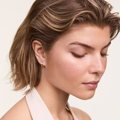 A woman wearing the Hoop + Crystal Heart Stud Rose Gold Set, featuring a rose gold hoop earring and a sparkling crystal heart stud styled together for a modern, elegant look.