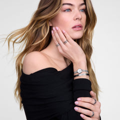 A woman wearing the Petite Mini Arch 3-link White Silver watch styled with silver jewellery and a black off-shoulder top, highlighting the watch’s petite stainless steel bracelet and minimalist white dial for an elegant, modern look.