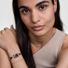 Woman wearing the Audrey Necklace Tiger Eye Gold, featuring a polished tiger eye pendant surrounded by cubic zirconia crystals on a gold chain, styled with matching jewellery and a neutral top.