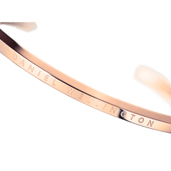 Classic Bracelet Rose Gold by Daniel Wellington, featuring a close-up of the engraved branding on the polished rose gold stainless steel cuff.
