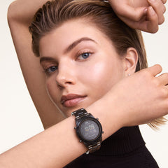 The Retro Digital Dark Grey Dark Grey watch by Daniel Wellington is shown worn on the wrist, highlighting its bold dark grey finish, digital display, and transparent bio-based plastic link strap styled with a black top.