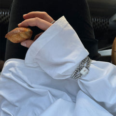 A woman wearing the Jolie & Chunky Chain Silver Set, featuring a Daniel Wellington silver watch with a square white dial and a matching chunky chain bracelet, styled with a white shirt for a modern, layered look.