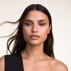 A woman wears the Crystal Zodiac Chain Necklace Silver, featuring a delicate silver chain and a sparkling Virgo zodiac pendant with hand-set crystals, styled with a black sleeveless top for a modern, understated look.