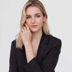 A woman wearing the Mirelle Solitaire Bracelet Silver, featuring a fine silver chain with a single cubic zirconia crystal, styled with a black blazer for a minimalist and elegant look.