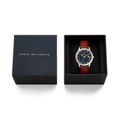 Iconic St Mawes Automatic Silver men’s watch with a brown leather strap and arctic blue enamel dial, presented in a navy Daniel Wellington gift box.