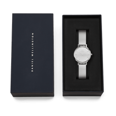 Daniel Wellington Petite Reflection Silver ladies watch with a mirror-effect silver dial and polished mesh strap, presented in an elegant black gift box with the brand name on the lid.