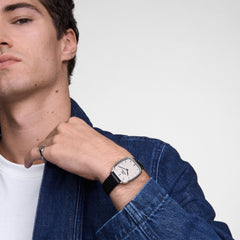 A man wearing the Marlon Sheffield Linen Silver watch with a rectangular stainless steel case, linen-textured dial, and black leather strap, styled with a denim jacket for a smart-casual look.