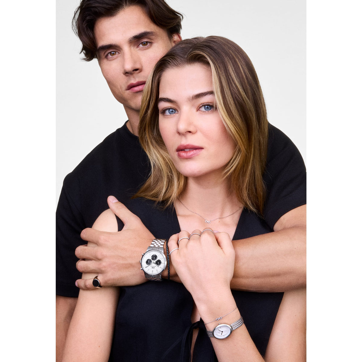 The Mirelle Infinity Necklace Silver is worn layered with other jewellery, showcasing its delicate infinity pendant with white cubic zirconia crystals on a fine silver chain, styled for an elegant everyday look.