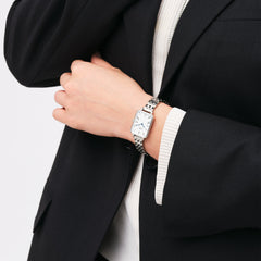 Quadro Roman Numerals 5-Link Silver watch worn on a wrist, featuring a rectangular white dial with roman numerals and blue hands, paired with a polished five-link silver strap and styled with a black blazer for a sophisticated business look.