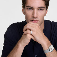 A man wearing the Marlon & Classic Mini Signet Ring Silver Set, featuring a polished silver signet ring with a cushion shape and a Daniel Wellington watch with a square yellow dial and silver mesh strap, styled with a dark shirt for a modern, refined look.