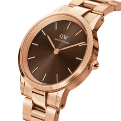 Close-up of the Daniel Wellington Iconic Link Amber watch, showing the sunray brown dial, rose gold stainless steel case, and polished bracelet with minimalist detailing.