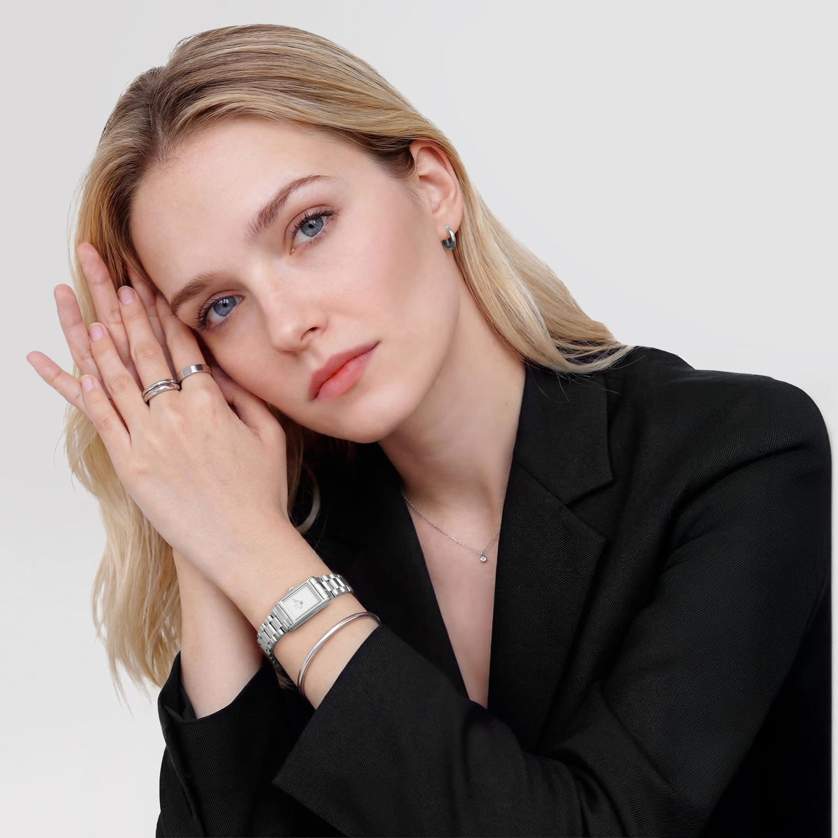 A woman wearing the Daniel Wellington Bound Mini 3-Link Silver watch with a slim rectangular case and polished silver bracelet, styled with a black blazer and silver jewellery for a modern, elegant look.