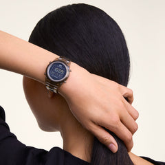 A person wearing the Daniel Wellington Retro Digital Dark Brown Dark Brown watch, showing its transparent dark brown link strap and round digital display with chronograph features, styled for everyday wear.
